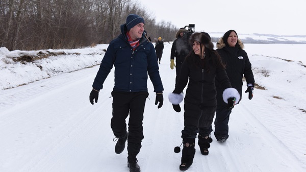 TV hosts and a cameraman walk through the snow.