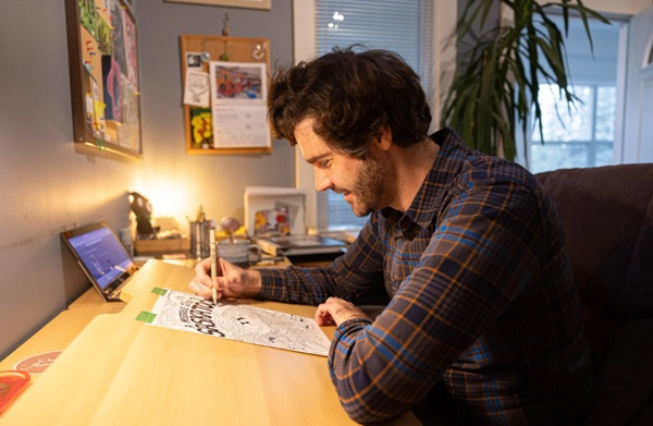 A comic book creator illustrates the cover of his book.