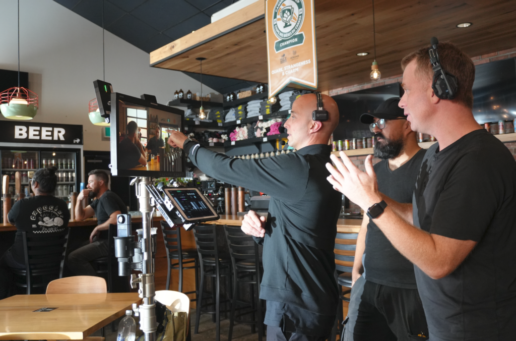 A camera crew provides direction in a pub scene.