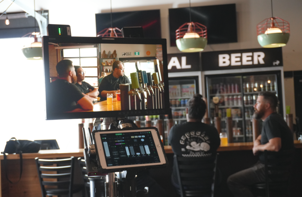 A screen records three men sitting at a bar.