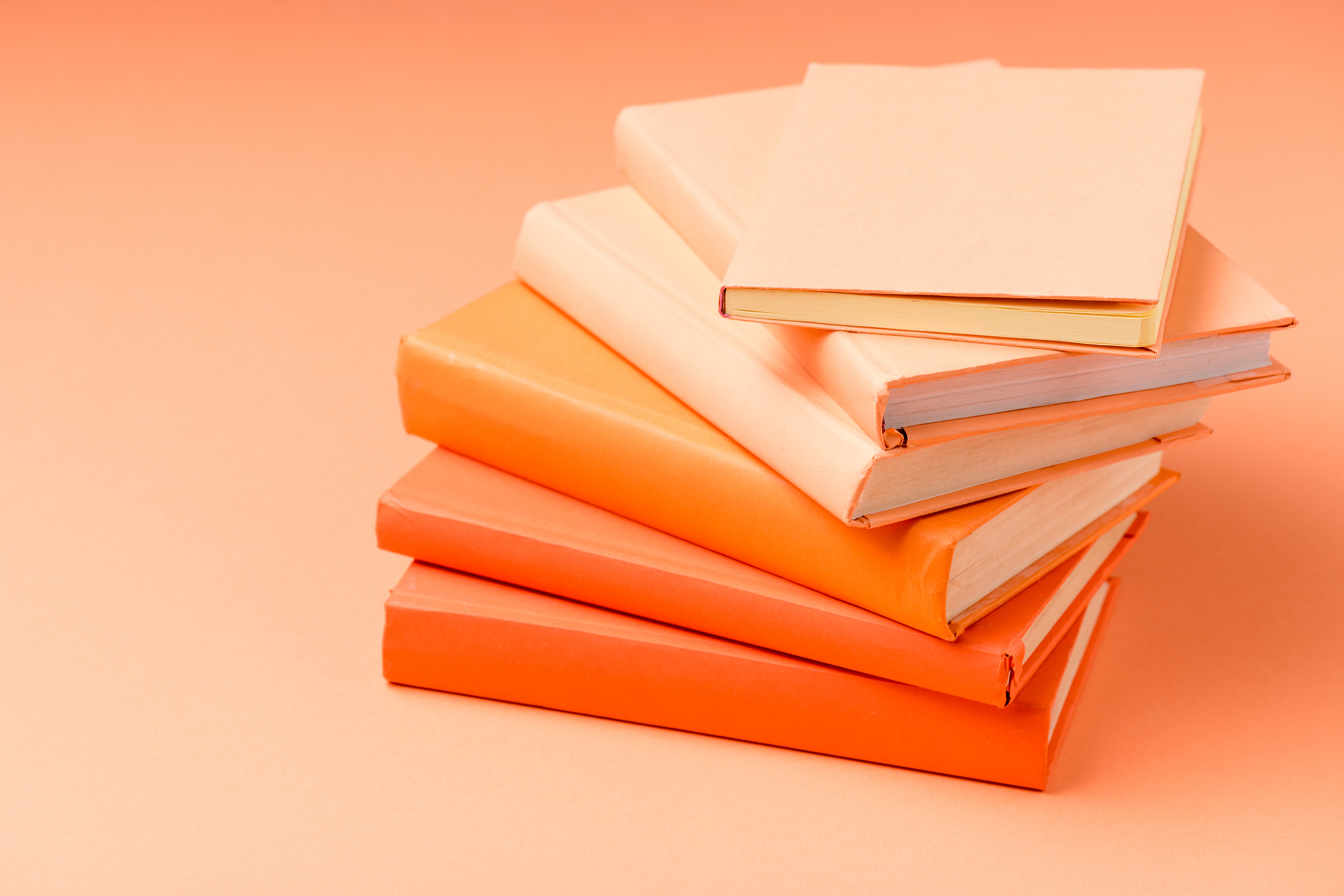 A stack of books on an orange background, their covers in varying shades of orange.