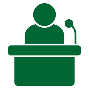 A green icon depicting a person speaking at a podium with a microphone.