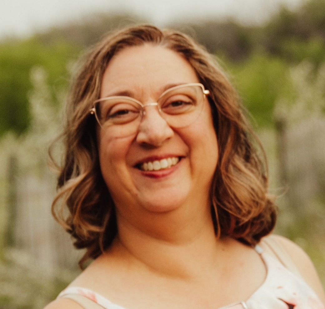 A smiling woman with shoulder length brown hair and classes.